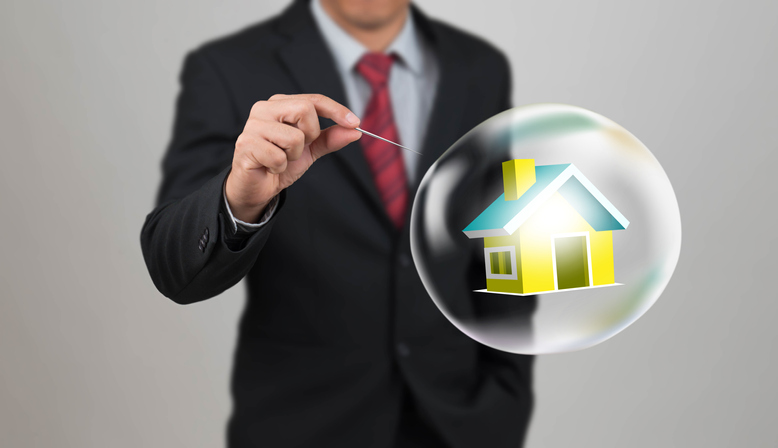 Man holding needle ready to pop a bubble with a house in it to demonstrat thinking beyond the housing bubble